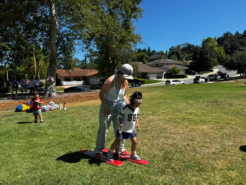 A coach works with a young child on the grass at a free class in Thousand Oaks