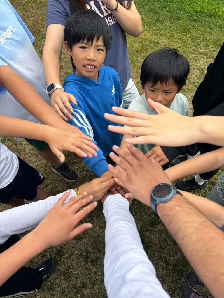 Children stack their hands in the middle of a circle before a session