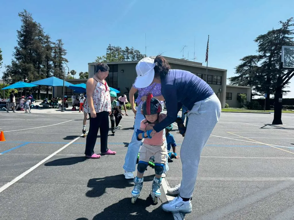 A coach steadies a child on roller skates at a free class in Arcadia