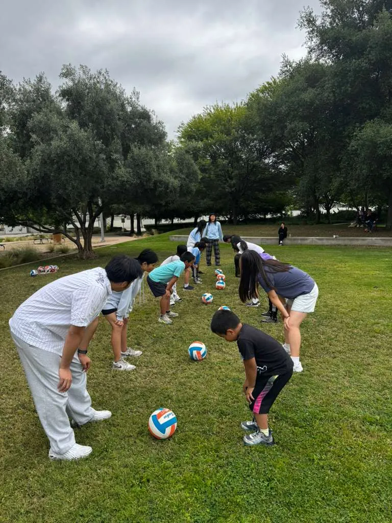Children bend over their soccer balls in a drill line at a free class in Rowland Heights