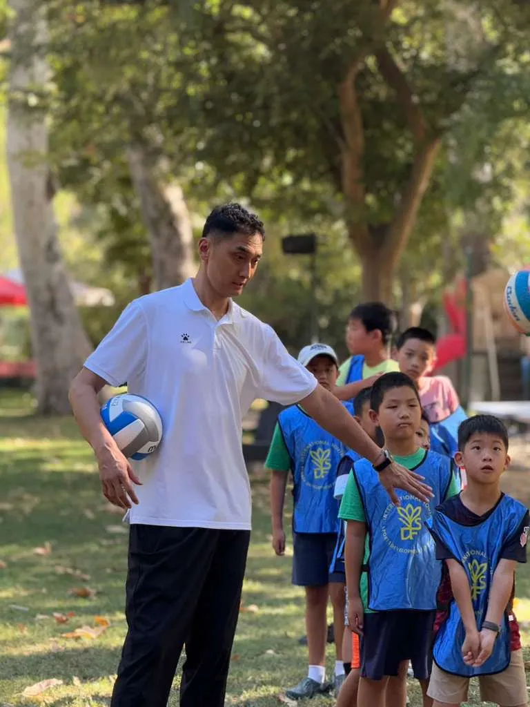 A coach holds a volleyball as children line up beside him at a free class in Agoura Hills