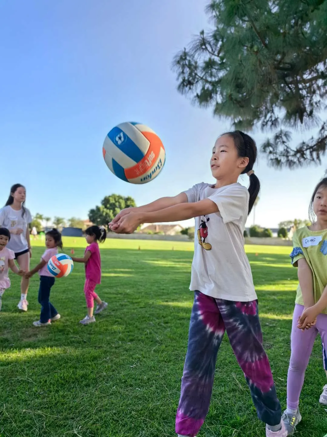A child reaches to play a volleyball at a free class in Irvine